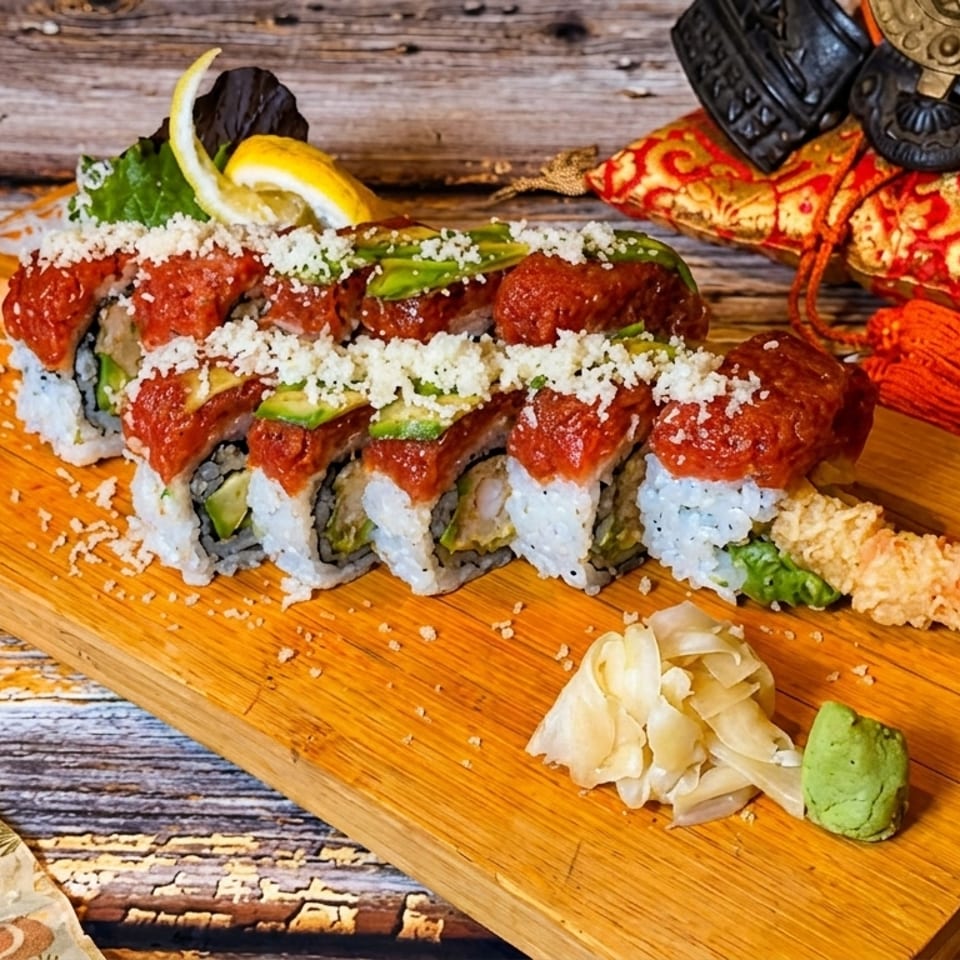 Sushi roll with red topping, avocado, and white flakes, served with tempura shrimp, ginger, and wasabi.